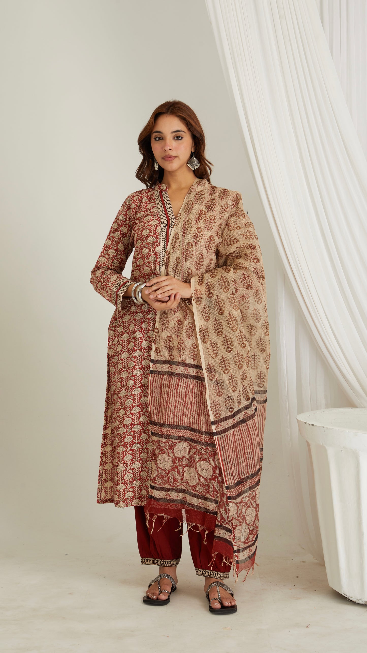 A woman wearing a traditional Kota Doria dupatta with hand block print in brown, red, and beige colors.