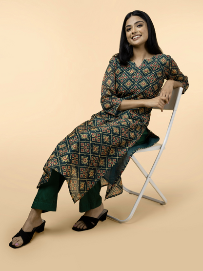 Woman sitting on a chair wearing a patterned kurta with a beige background